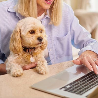 A woman works on laptop holding her dog