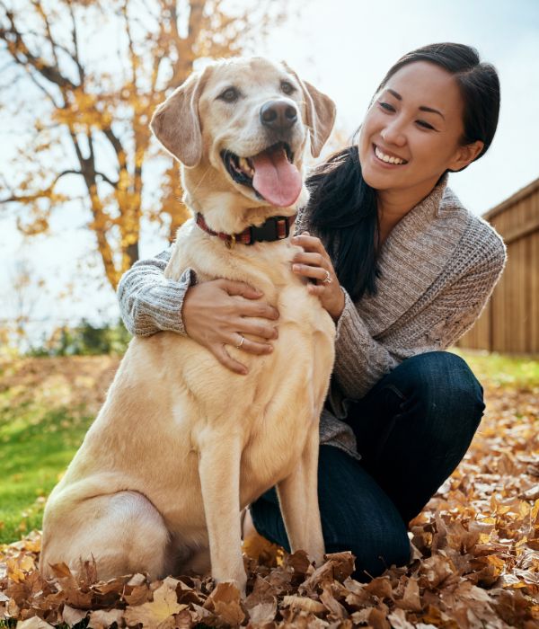 A woman is seated on the ground, affectionately petting her dog